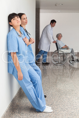Two nurses leaning on wall