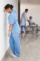 Distressed nurse standing against wall