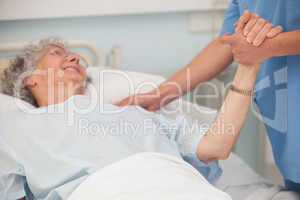 Elderly patient holding hand of nurse