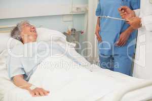 Elderly female patient smiling up at nurse and doctor