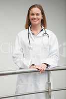 Female doctor smiling and leaning against railing