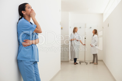 Nurse looking up and leaning against wall