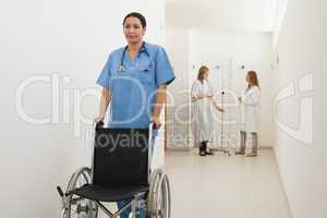 Nurse pushing empty wheelchair