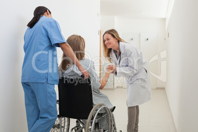 Doctor talking to patient in wheelchair while nurse is pushing