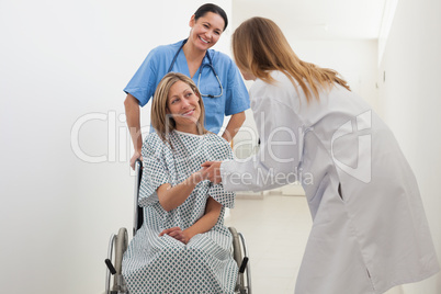 Patient in wheelchair shaking hands with doctor
