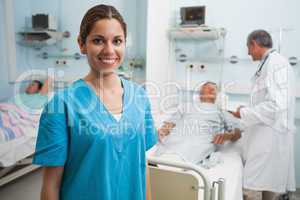 Happy nurse standing in hospital room