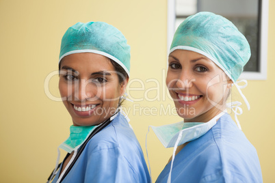 Two happy women wearing scrubs in hospital room