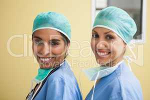 Two happy women wearing scrubs in hospital room