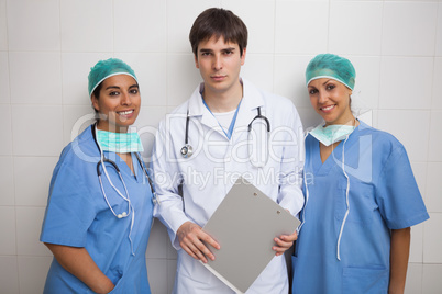 Doctor with clipboard stands between two nurses