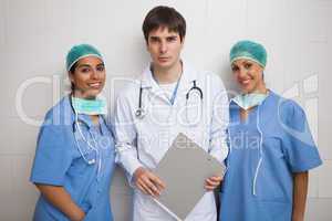Doctor with clipboard stands between two nurses