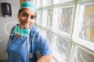 Happy nurse leans against glass wall