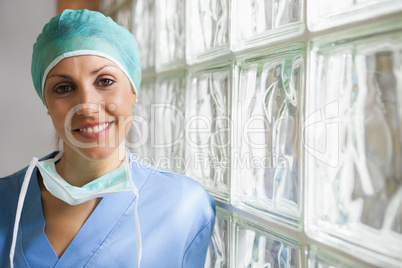 Nurse wearing surgical cap leaning against glass wall