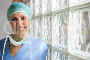 Nurse wearing surgical cap leaning against glass wall