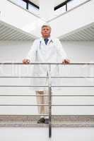 Thinking doctor stands at railing