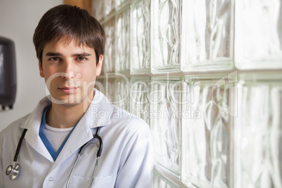 Doctor leans against glass wall