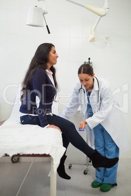 Doctor is looking at the leg of the woman