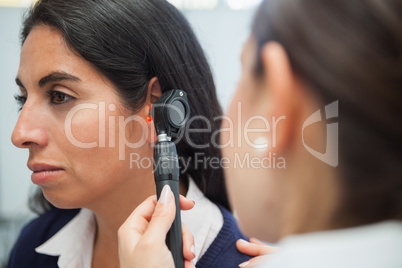 Doctor using otoscope to check womans ear