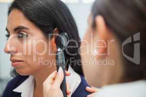 Doctor using otoscope to check womans ear