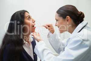 Smiling doctor looking into patients mouth