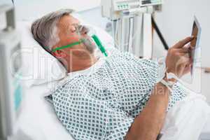 Patient is lying in bed reading in hospital ward