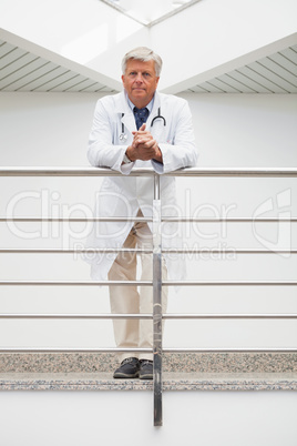 Doctor leaning on rail in hospital corridor