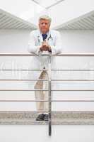 Doctor leaning on rail in hospital corridor