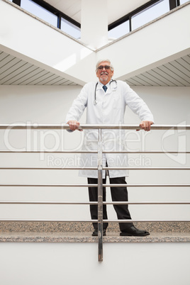 Happy doctor leans against rail