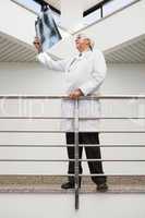 Doctor looking at x-ray leaning against railing