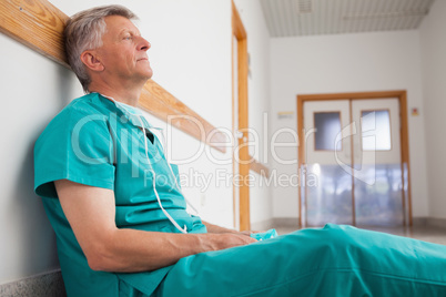 Tired surgeon is sitting on the floor in hospital corridor