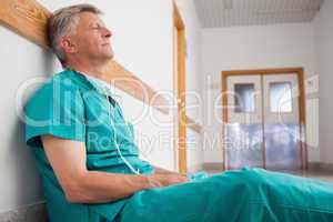 Tired surgeon is sitting on the floor in hospital corridor