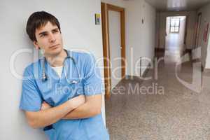 Nurse is leaning on the wall on the corridor and thinking