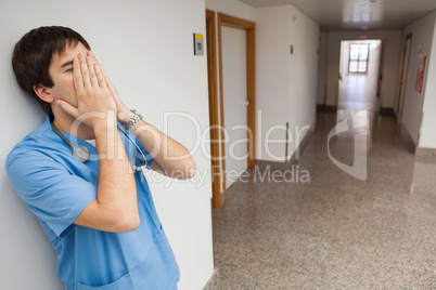 Nurse with hands in face in hospital corridor