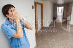 Nurse with hands in face in hospital corridor