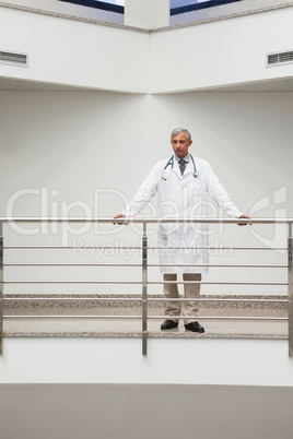 Doctor is standing a the railing of the corridor