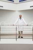 Doctor is standing a the railing of the corridor