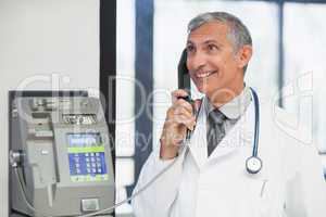 Doctor on a payphone and smiling in hospital