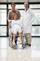 Pregnant woman in wheelchair, partner and doctor smiling