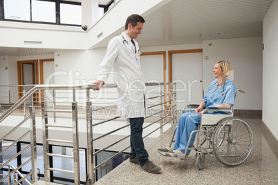 Doctor talks to nurse sitting in wheelchair