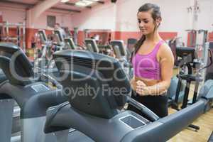 Woman running on a treadmill in a gym looking down