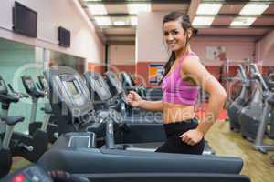 Woman running on a treadmill in a gym looking happy