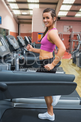 Smiling woman running on a treadmill in the gym