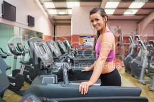Smiling woman on a treadmill in the gym taking a break