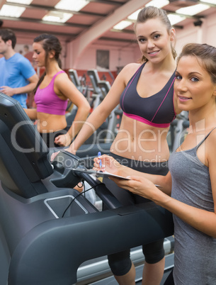 Happy woman and instructor in the gym