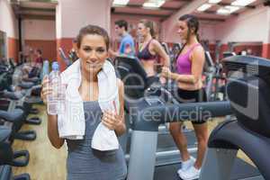 Happy woman drinking water in gym