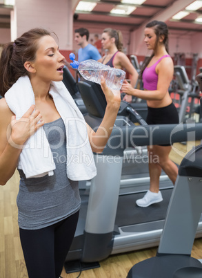 Woman drinking bottle of water in the gym