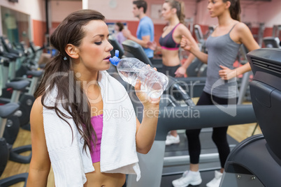 Woman drinking water beside treadmill