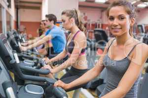 Smiling woman with other people riding an exercise bike