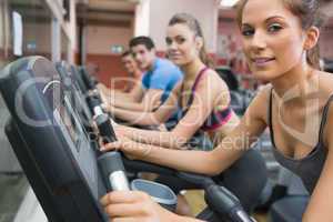 Four people smiling and riding on an exercise bike