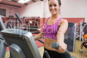 Smiling brunette stepping on a step machine