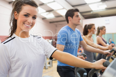 Smiling brunette with other people  on a step machine